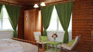 A wooden cabin room with a bed, two chairs, a table, and a wardrobe. - Vita Ristorante Gasthof (Rastenfeld)