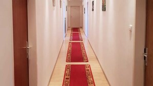 A hotel hallway with a red carpet, wooden doors, and recessed lighting. - Vita Ristorante Gasthof (Rastenfeld)
