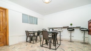 Un comedor con puerta de madera, ventana, suelo de baldosas y una barra con taburetes.
