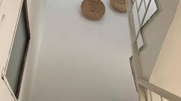 Una escalera con una pared blanca y una ventana a la izquierda, que conduce a una plataforma.