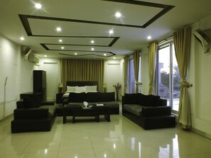 A modern living room with a large bed, a sofa, a coffee table, and a TV. - Capetown Guest House (Islamabad)