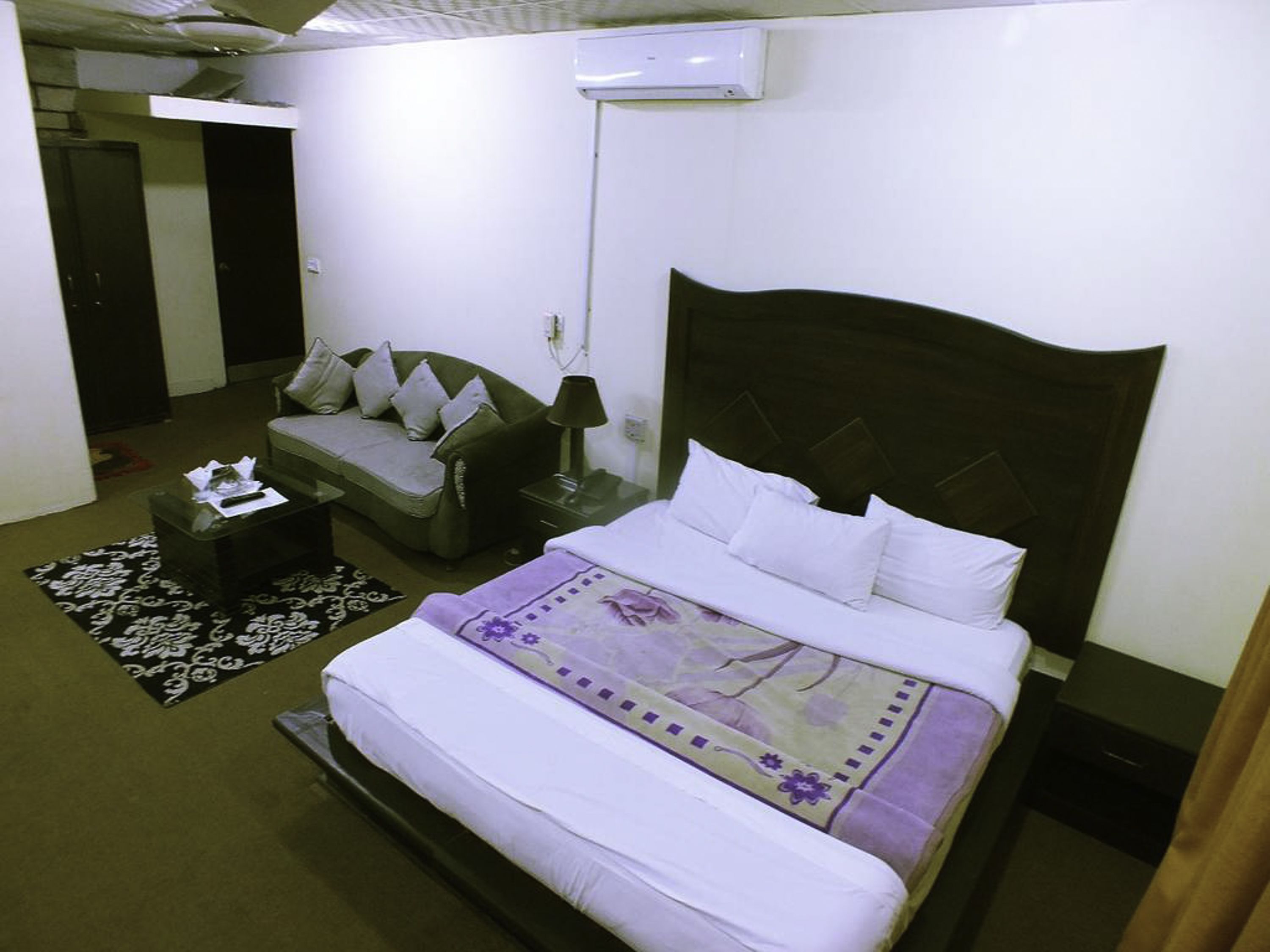 Una habitación de hotel con cama, sofá, mesita de noche y lámpara.