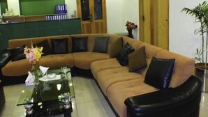 A modern living room with a sectional sofa, a coffee table, and a potted plant. - Capetown Guest House (Islamabad)
