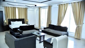 A hotel room with a bed, two sofas, a coffee table, and a chair. - Capetown Guest House (Islamabad)