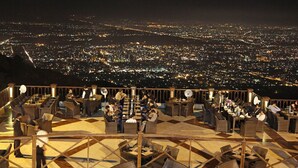 A rooftop bar with outdoor seating overlooking a cityscape at night. - Capetown Guest House (Islamabad)