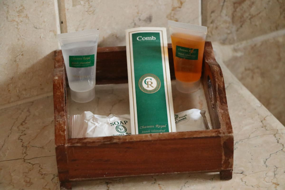 A wooden tray containing toiletries including soap and shampoo, placed on a marble surface.
