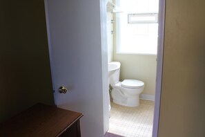 Une petite salle de bain étroite, avec des toilettes et un lavabo.