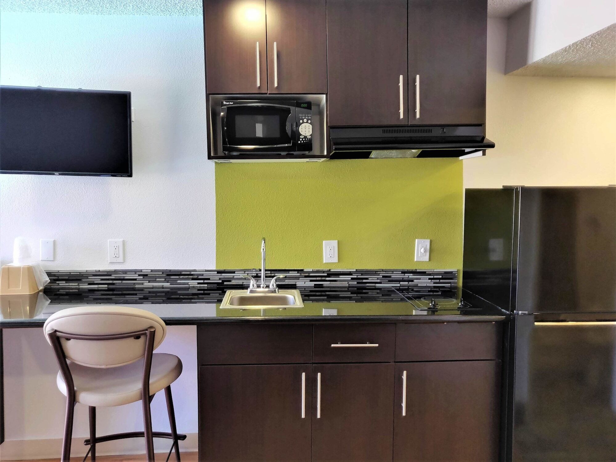 A compact kitchen with a microwave, sink, and refrigerator.