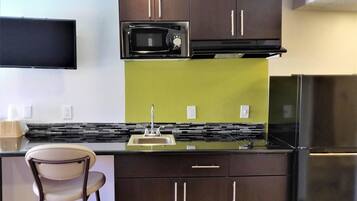 A compact kitchen with a microwave, sink, and refrigerator.