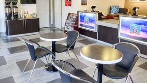 Eine moderne Hotelhalle mit Empfangstresen, Sitzgelegenheiten und einer Kaffeestation.