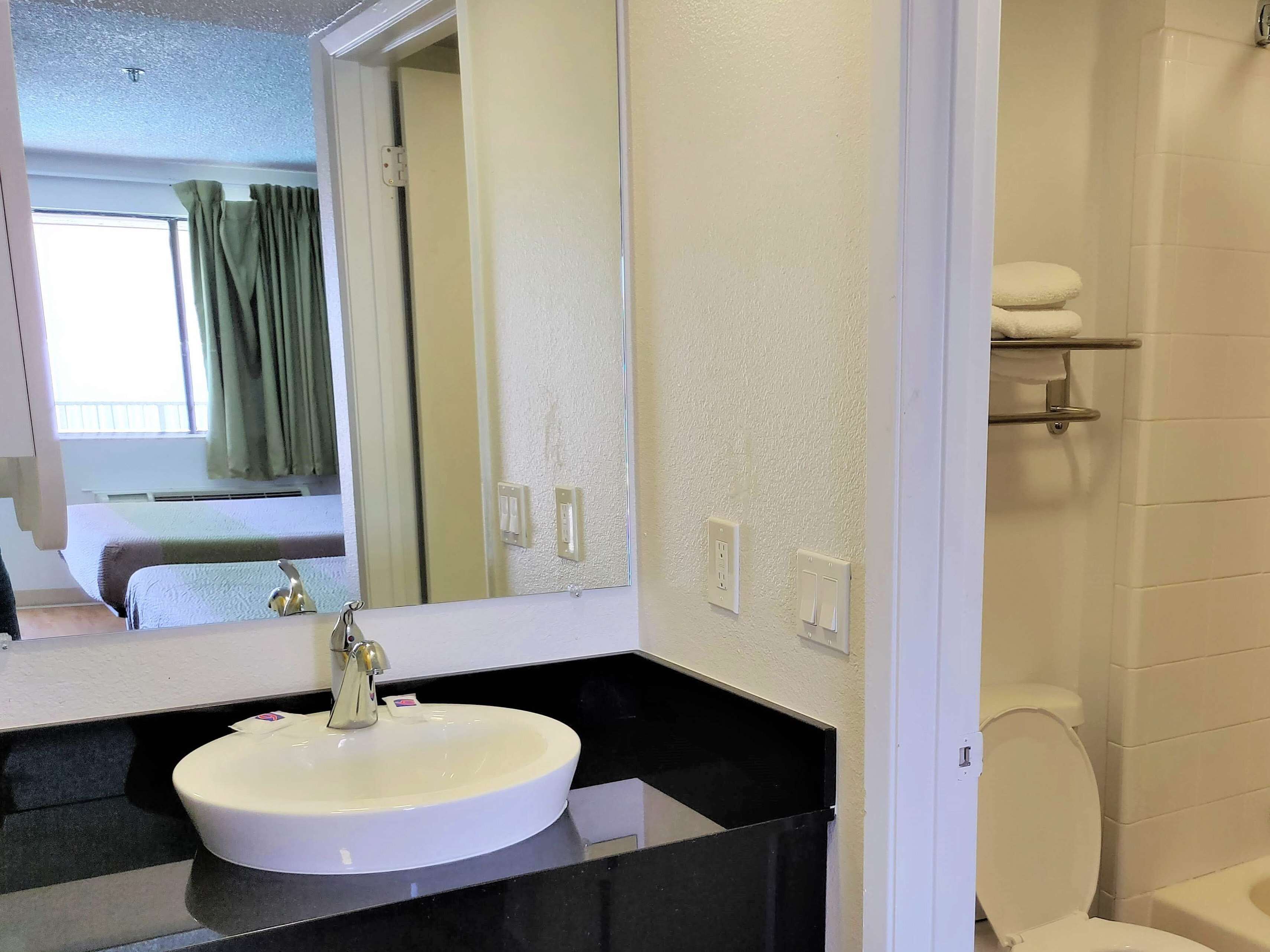 A bathroom with a white sink, a mirror, and a toilet.