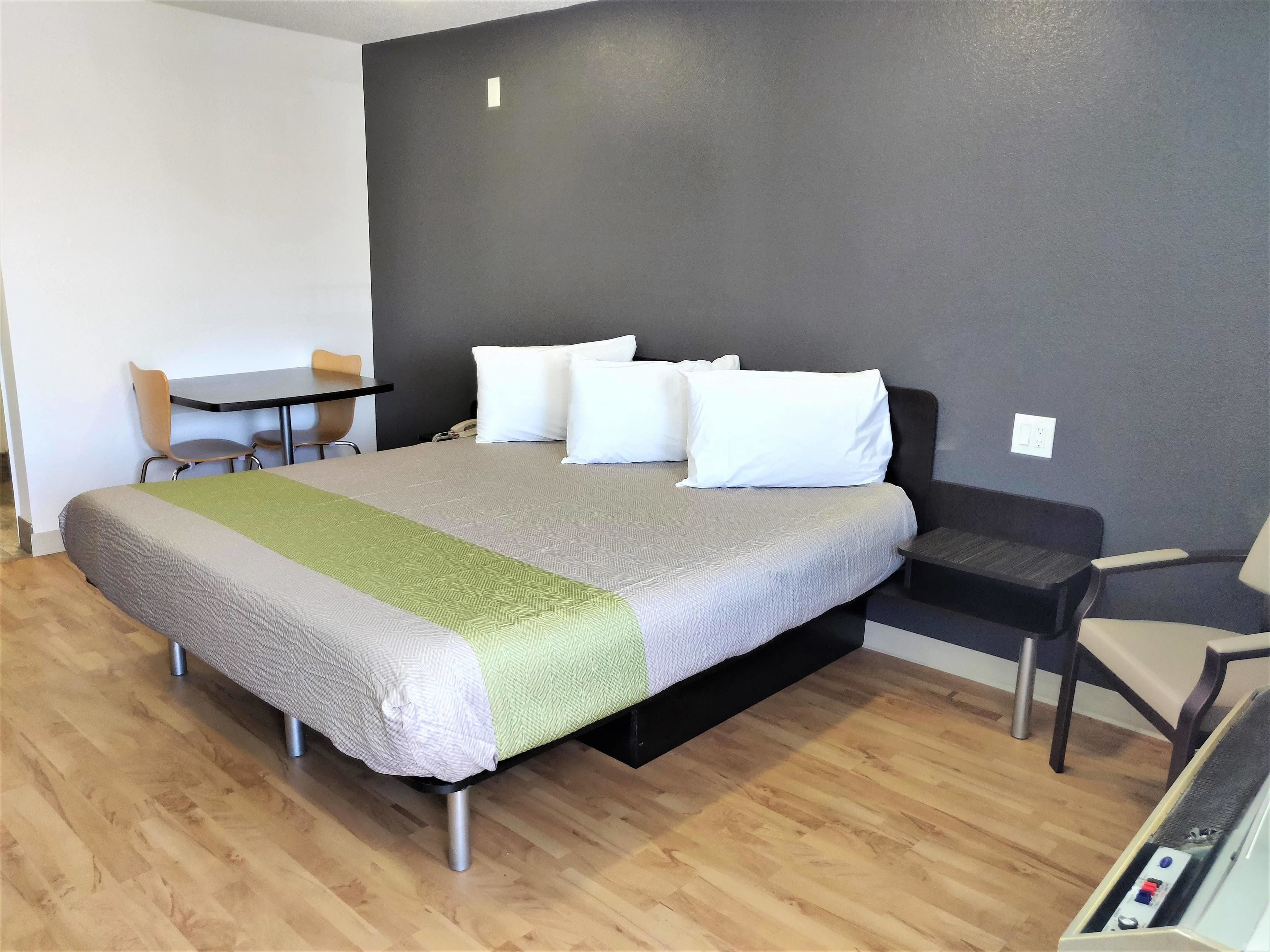 A modern hotel room with a large bed, a desk, and a chair.