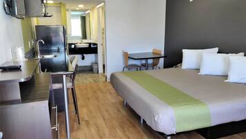 Une chambre d’hôtel avec un lit, un bureau, une chaise, une télévision et une salle de bain.