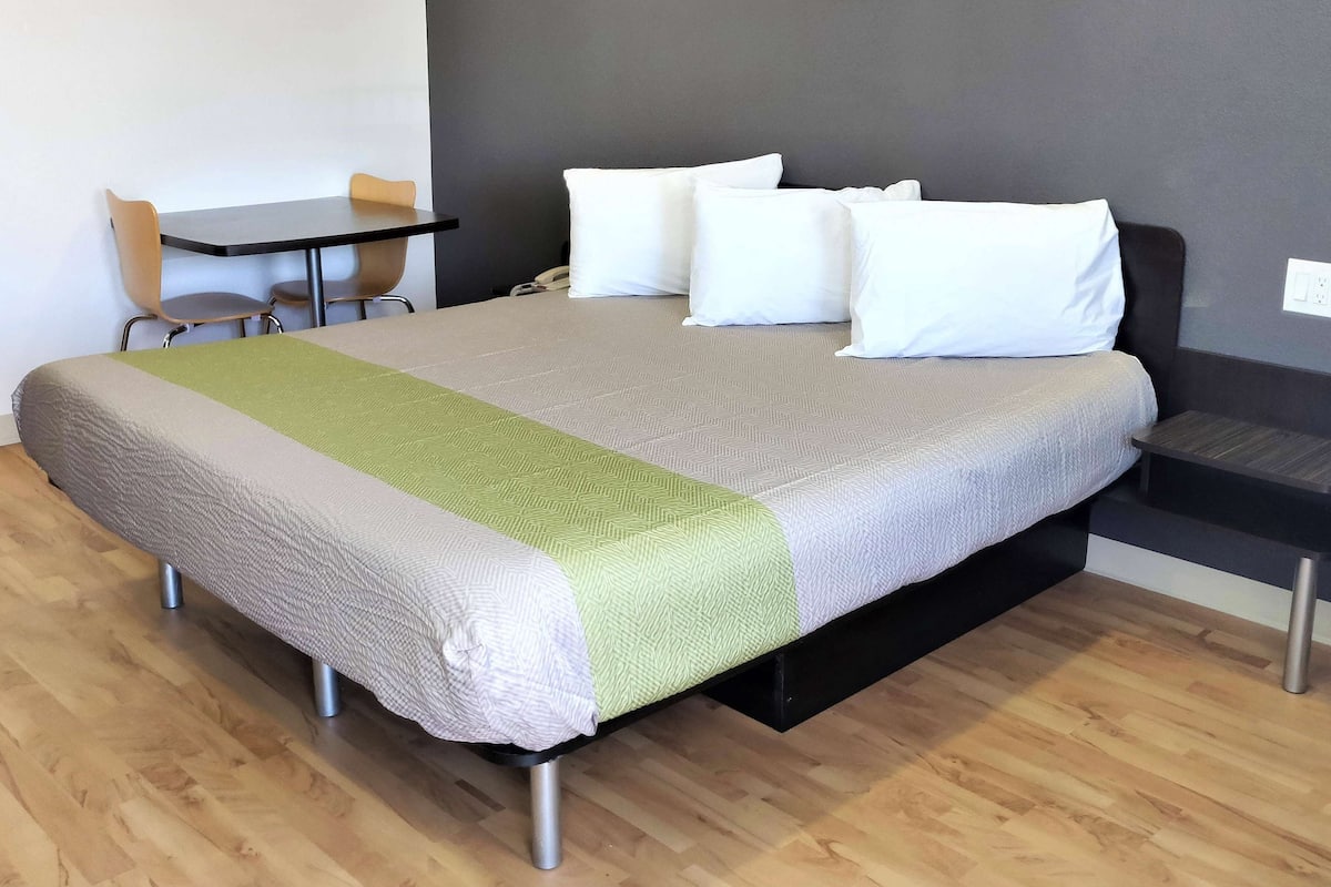 A neatly arranged hotel room with a large bed, a small desk, and a chair.