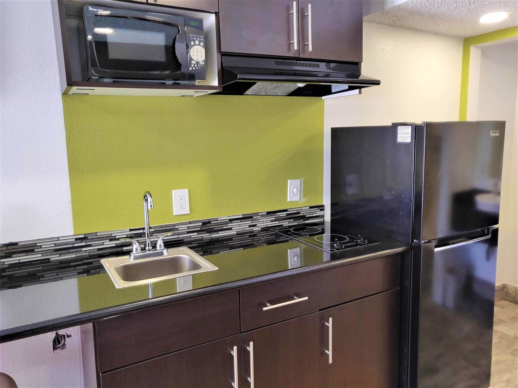 Una cocina compacta con microondas, refrigerador y fregadero.