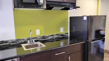 Una cocina compacta con microondas, refrigerador y fregadero.