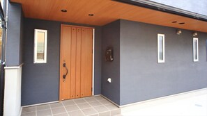 A modern building exterior with a wooden door, a small window, and a wall-mounted light fixture. - COTO Tokyo Shibuya 4 (Tokyo)