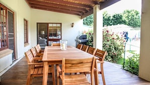 A wooden deck with a table and chairs, a grill, and a view of greenery. - Brigham House (Tooma)