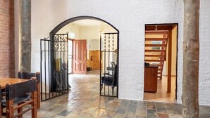 A spacious hall with a tiled floor, a wooden table with chairs, and a staircase with a railing. - Brigham House (Tooma)