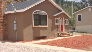 A small, single-story building with a red door and a mailbox.