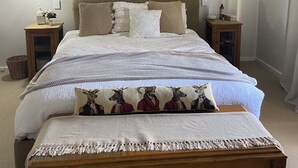 Ein Schlafzimmer mit einem großen Bett, zwei Nachttischen, einer Pendelleuchte und einem an der Wand hängenden Kunstwerk.