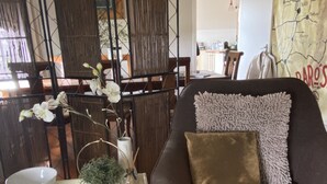 Ein Wohnzimmer mit grauem Sofa, einem weißen Beistelltisch und einem dekorativen Raumteiler mit vertikalen Lamellen.