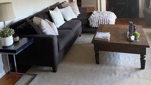 Ein Wohnzimmer mit einem dunklen Sofa, einem Couchtisch, einer Lampe und einem Kamin.