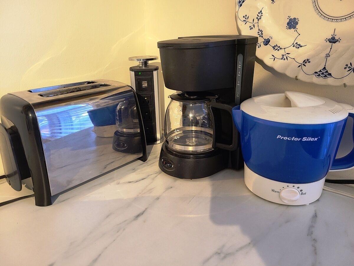 Ett kök med en brödrost, en kaffebryggare och en mugg från Proctor Silex.