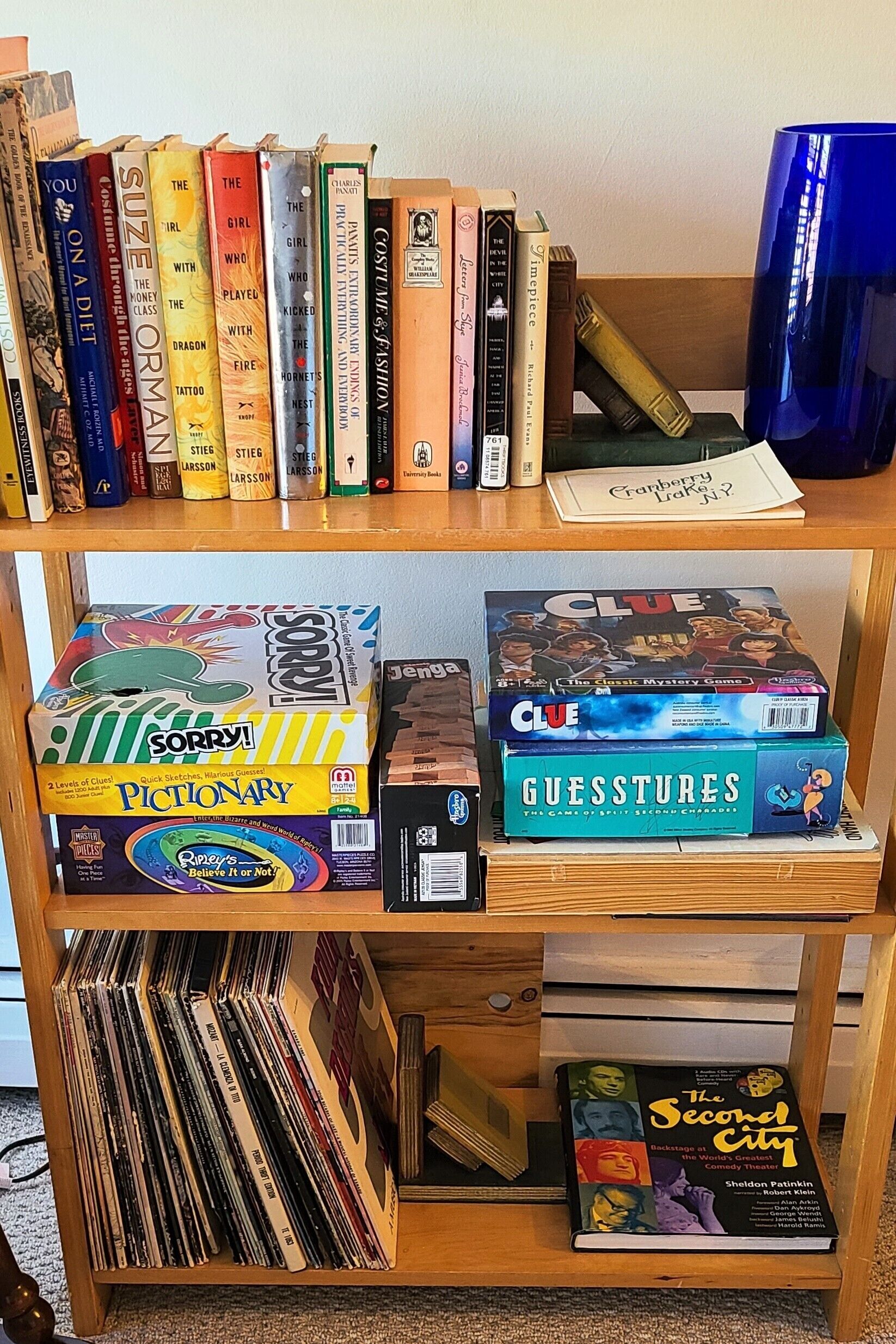 Una estantería con varios libros y juegos, incluyendo 'Sorry!', 'Pictionary' y 'Clue'.