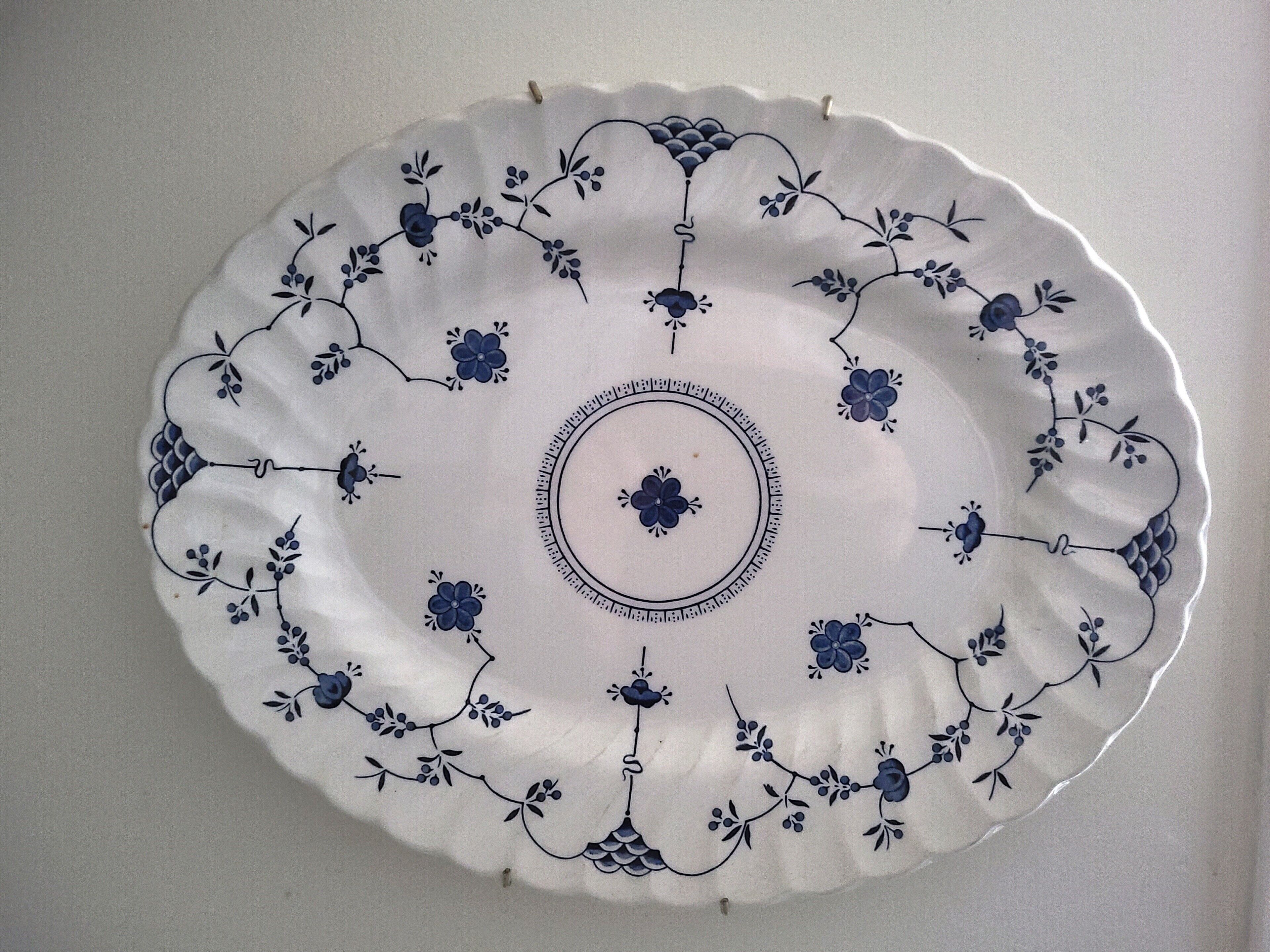 Une assiette blanche ornée de motifs floraux bleus et d’un motif central.