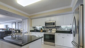 Una cocina moderna con armarios blancos, electrodomésticos de acero inoxidable y encimera de granito negro.