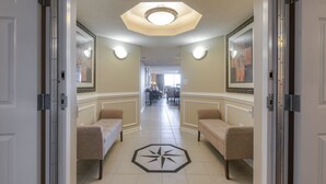 Un pasillo de hotel con dos sofás, un suelo estampado con motivos de estrellas y un comedor a lo lejos.