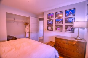 A bedroom with a bed, a dresser, a mirror, and a wall with framed pictures.