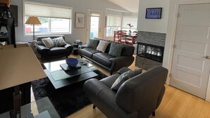 A modern living room with a sofa, armchairs, a coffee table, and a fireplace. -  N TacomaPt Ruston 2bd. 2bath retreat w/ EV charger, A/C & relaxing water views (Tacoma)