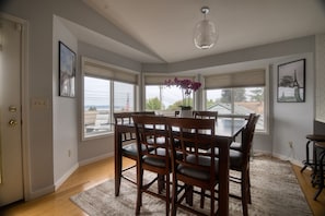 A dining area with a table and chairs, large windows, and a view of the outdoors.