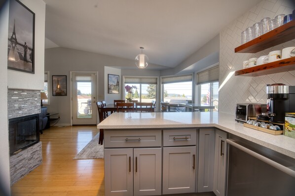 A modern kitchen with a central island, wooden cabinets, and a dining area with a view.