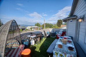 A backyard with a grill, outdoor furniture, and a table set for dining.