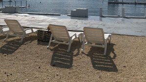 Eine Strandbucht mit Liegestühlen und einem Steg, der ins Wasser führt.