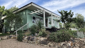 Una casa moderna con porche cubierto, muros de piedra y diversas plantas.