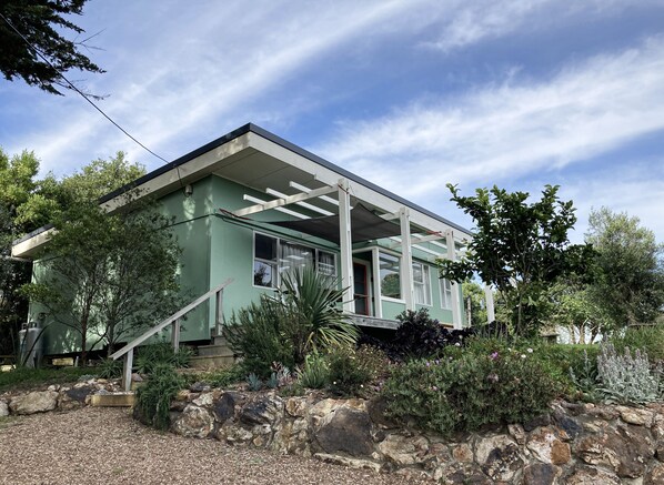 A modern house with a covered porch, stone walls, and a variety of plants.