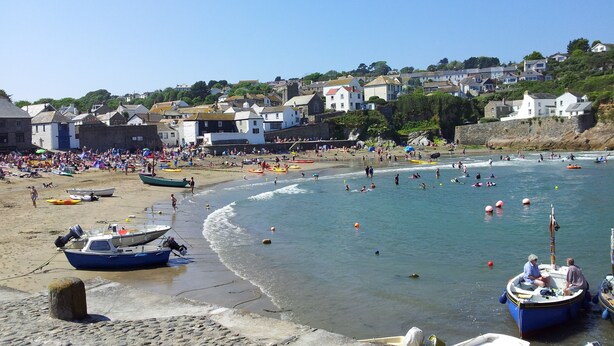 A beach with boats, people, and houses in the background.