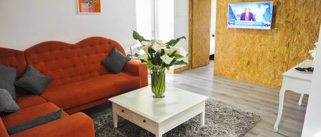 A modern living room with a red sofa, a white coffee table, and a TV mounted on a wooden wall.