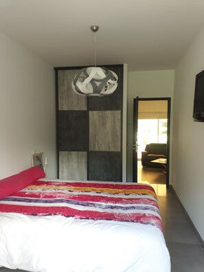 Un dormitorio moderno con una cama grande, una lámpara de techo original y vistas a otra habitación.