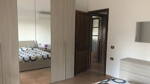Un dormitorio con cama, armario y puerta que da a un balcón.