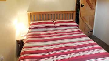Un lit avec une couvre-lit à rayures, une tête de lit en bois et une table de chevet avec une lampe.