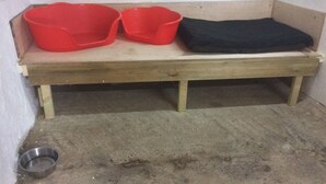 A wooden bench with two red plastic containers and a black cloth on top. - Grooms Cottage- Sleeps 4 in 2 bedrooms plus 2 to 4 dogs depending on size. (Bodmin)