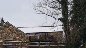 A stone building with a wooden fence and a dog in a snowy field. - Grooms Cottage- Sleeps 4 in 2 bedrooms plus 2 to 4 dogs depending on size. (Bodmin)