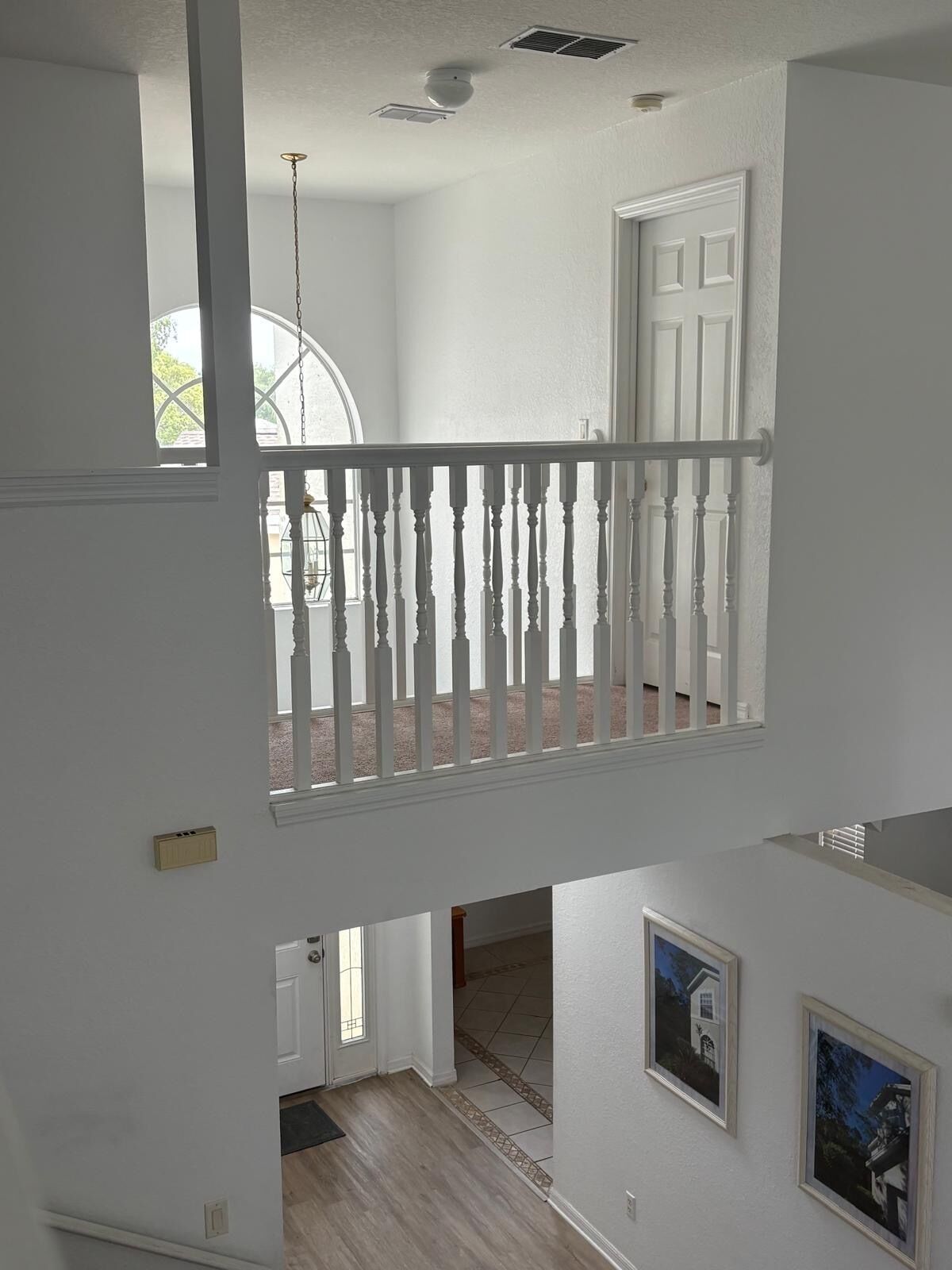 Un intérieur à plusieurs niveaux, avec une rambarde blanche, une porte et une fenêtre.