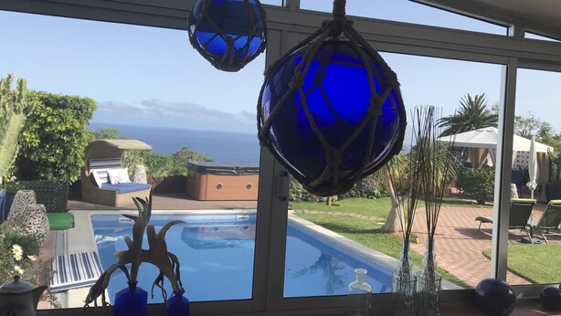 Ein Zimmer mit großem Fenster, das einen Blick auf einen Pool und das Meer bietet.