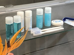 A bathroom shelf with various toiletries including shampoo, body lotion, and toothbrushes.